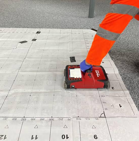 Hilti scanner being used over a gridded floor plan during a non intrusive condition survey
